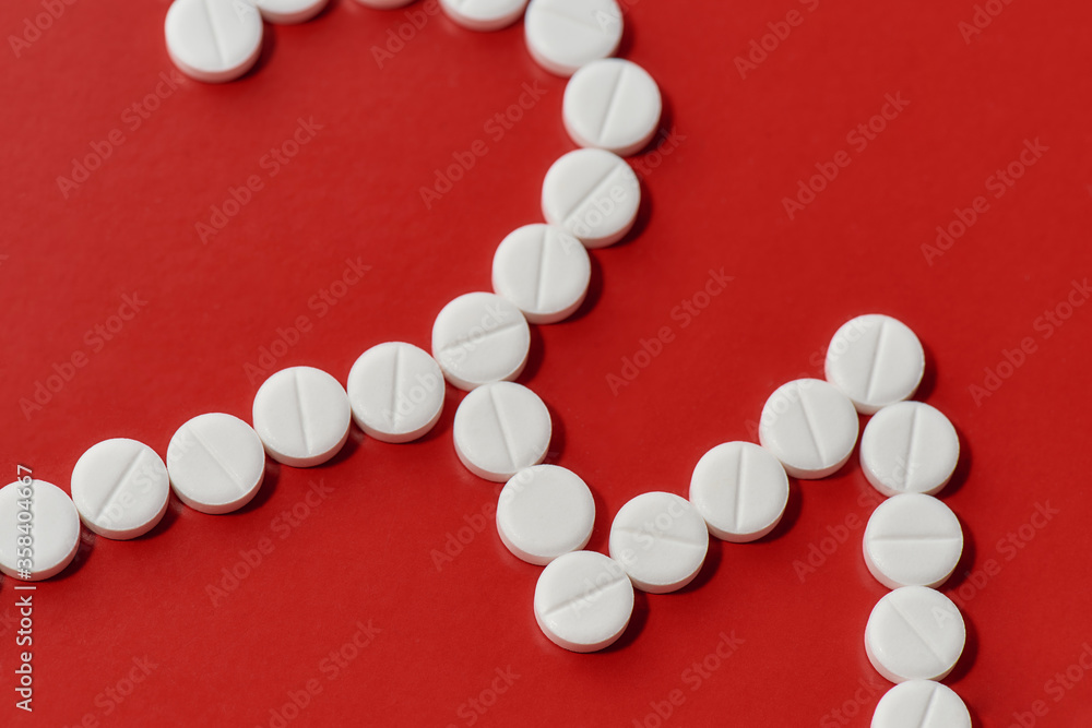 Close up of heart and cardiogram made of white pills over red background. Heart and cardiovascular disease, health and treatment concept Close up of heart and cardiogram made of white pills over red background. Heart and cardiovascular disease, health and treatment concept