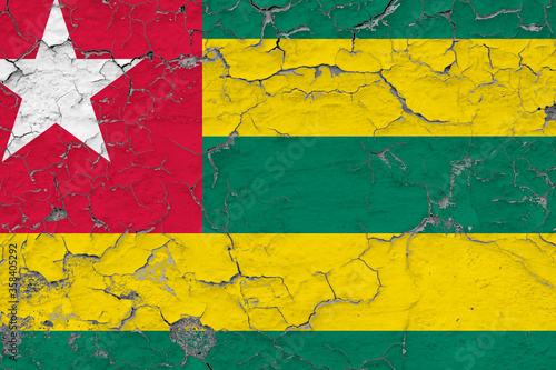 Togo flag close up grungy, damaged and weathered on wall peeling off paint to see inside surface. Vintage concept.