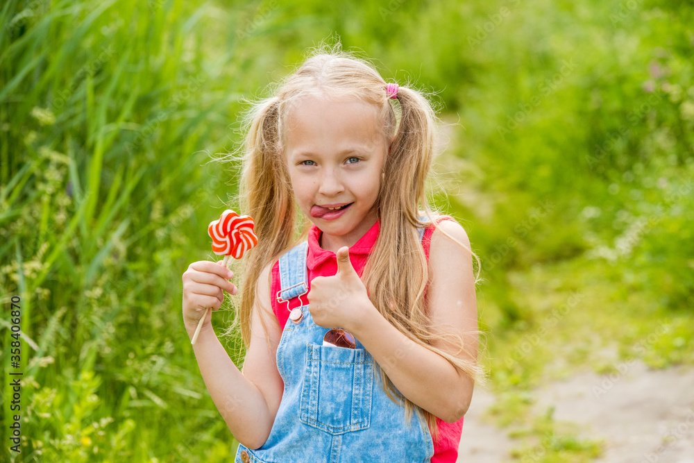 Blonde little girl with long hair and candy on a stick Blonde little girl with long hair and candy on a stick