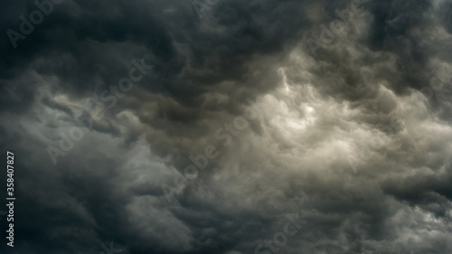 gray gloomy sky before the storm with unusual bizarre patterns of dense cumulus clouds and back light. panoramic view. Artistic picture for mystical design or decoration
