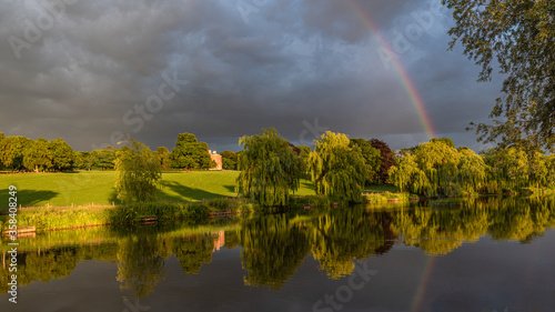 Wedgwood pools and Barlaston Hall. A landscape view with sunlight, stormy sky and rainbow reflected in the water