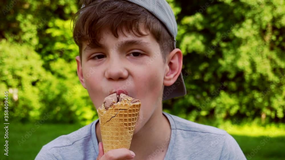 teenager boy eating ice cream outdoors on a hot sunny day teenager boy eating ice cream outdoors on a hot sunny day