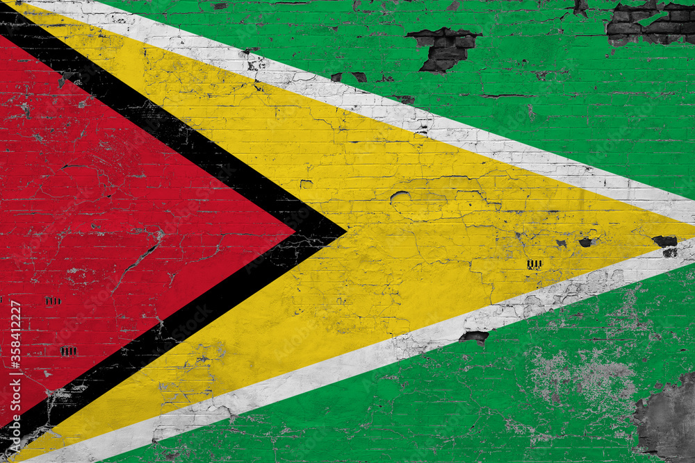 Guyana flag on grunge scratched concrete surface. National vintage background. Retro wall concept.