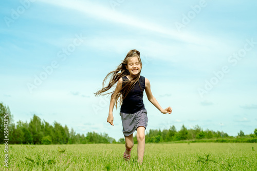 Little girl running on a meadow in a field of flowers, Freedom, happiness and wind in your hair.