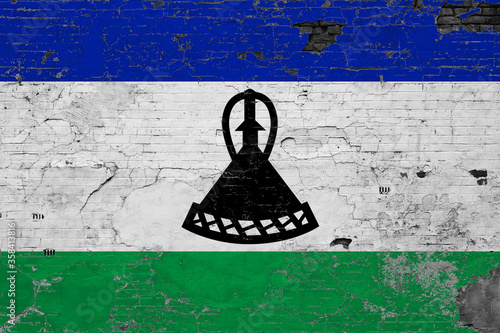 Lesotho flag on grunge scratched concrete surface. National vintage background. Retro wall concept.