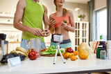 Sharing ideas. Cropped shot of couple recording video blog or vlog about healthy nutrition at home. Man and woman showing ingredients and explaining how to cook a dish, standing in the kitchen
