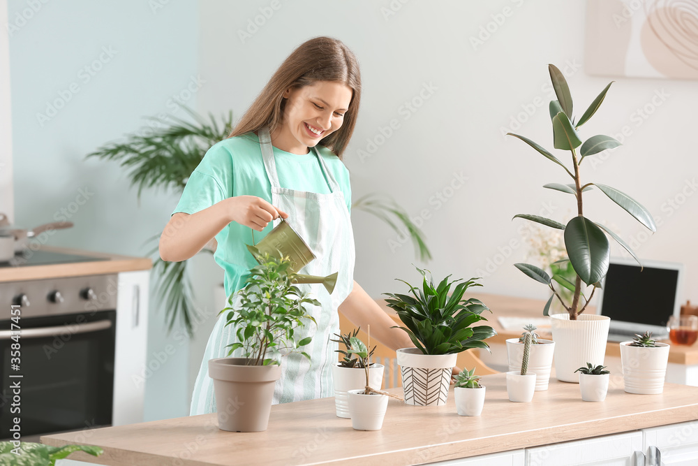 Young woman watering plants at home