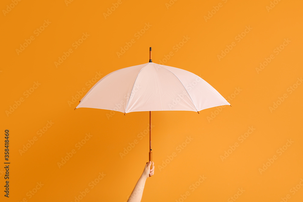 Hand with stylish umbrella on color background