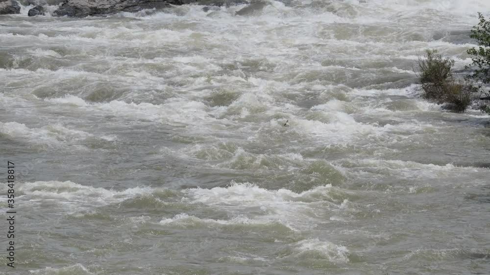 The Serio river swollen after heavy rains. Province of Bergamo, northern Italy. Brown water. The water flows fast from the high valley to the plain The Serio river swollen after heavy rains. Province of Bergamo, northern Italy. Brown water. The water flows fast from the high valley to the plain