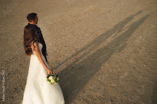 Tableau sur toile Wedding couple walking on sandy beach