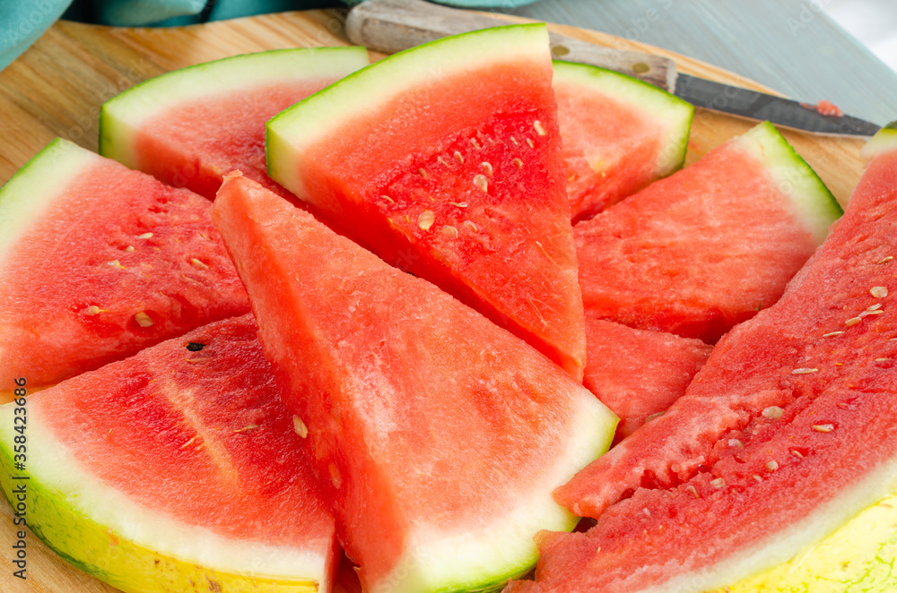 Slices of watermelon on a wood cutting board and wooden background