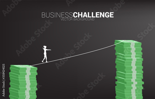 Silhouette of businesswoman walking on rope walk way to higher banknote stack .Concept for business risk and career path