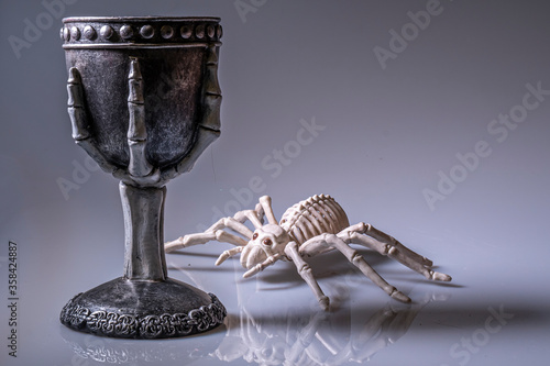 Tarantula skeleton inspects a goblet of poison.