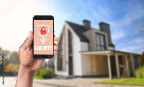 Alarm system. African-American man using phone outdoors, space for text