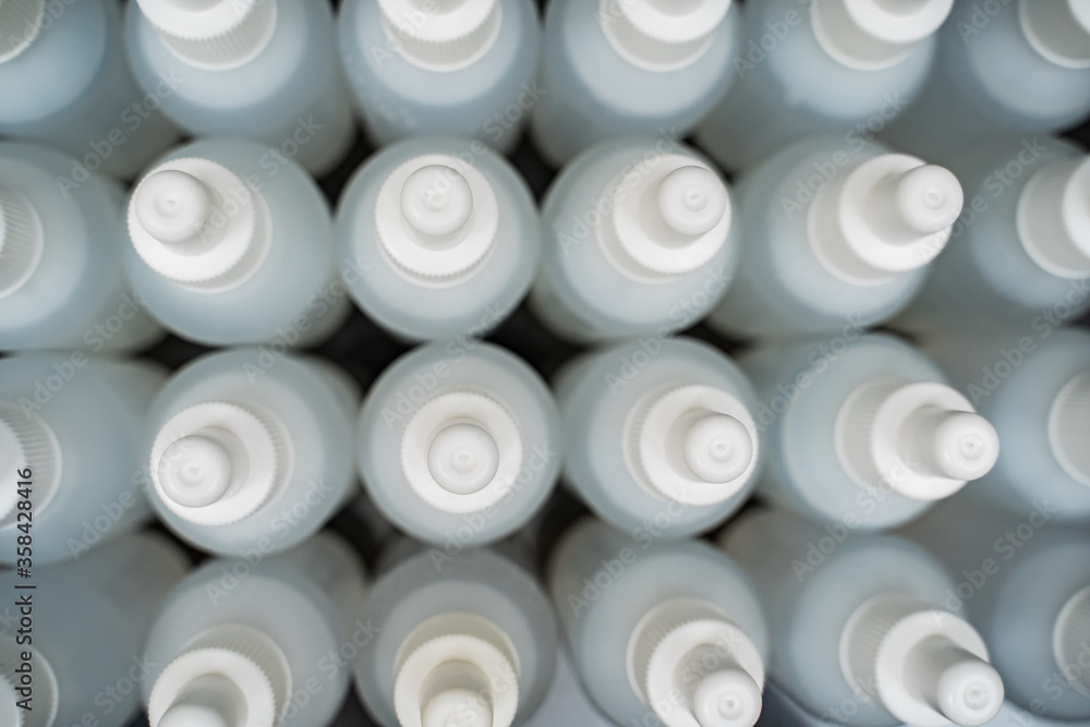 A lot of white bottles filled with liquid. Manufacture of antiseptics A lot of white bottles filled with liquid. Manufacture of antiseptics