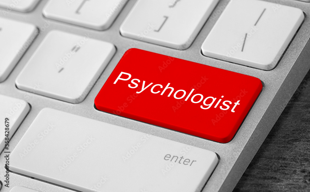 Fototapeta premium Modern computer keyboard with word PSYCHOLOGIST on table, closeup