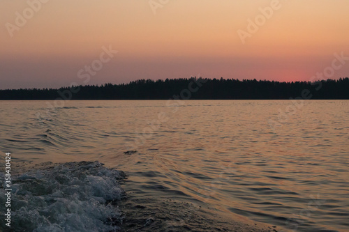 Russia  Karelia. White nights. Dawn on Lake Muezero. Dawn on Lake Muezero. Trail from a boat motor on a lake.