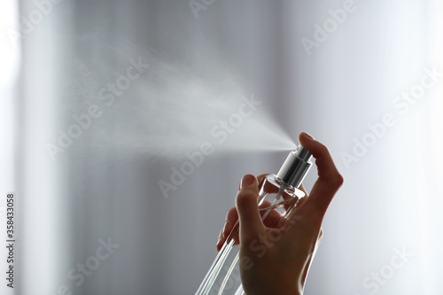 Quadro su tela Woman spraying air freshener indoors closeup. Space for text