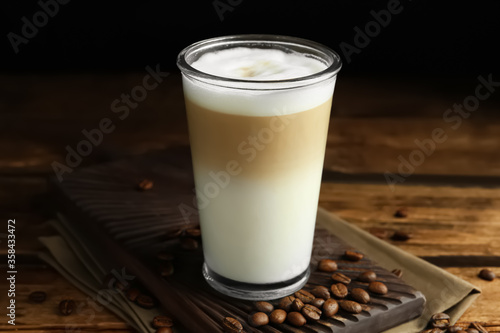 Delicious latte macchiato and coffee beans on wooden table