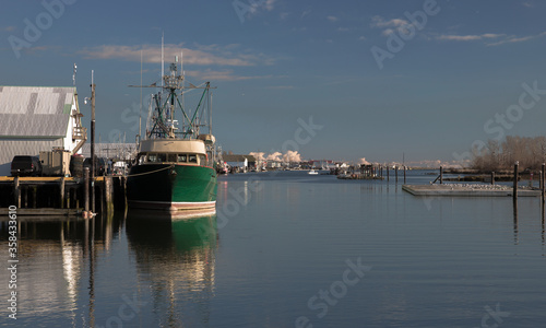 Fishing trawler at the pier in Richmond s fishing commercial area among commercial buildings and a bright blue sky