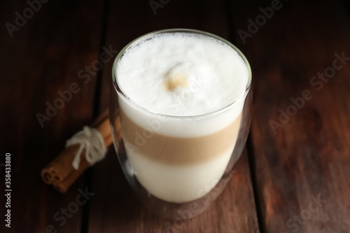Delicious latte macchiato and cinnamon on wooden table