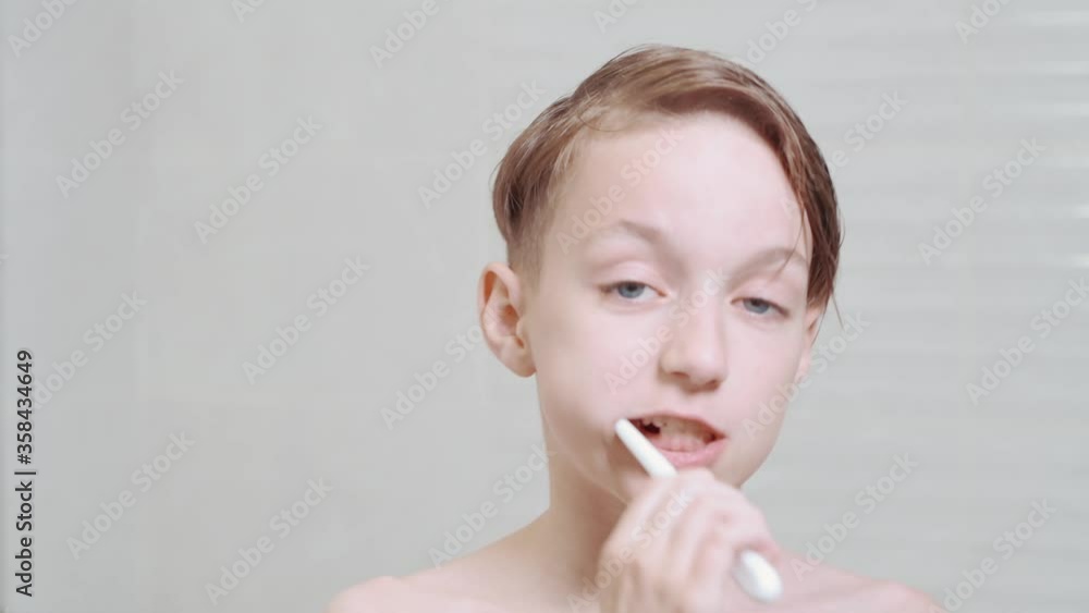 Funny brunette boy brushes his teeth and dances in the bathroom near the mirror. Funny brunette boy brushes his teeth and dances in the bathroom near the mirror.