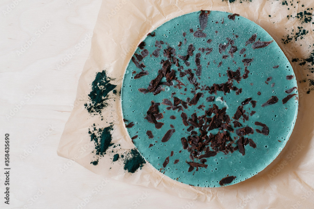 Green vegan cake with spirulina. Homemade baking. Top view copyspace. Delicious round tart with spirulina on the wooden table.