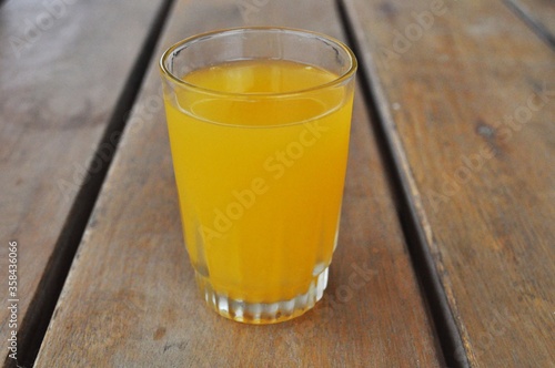 Glass of orange juice on wooden background