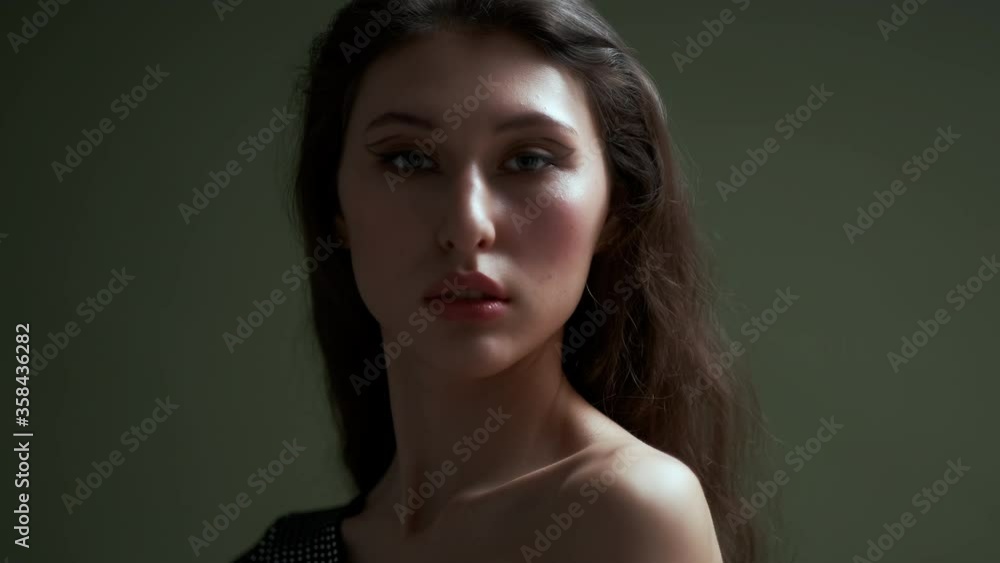 A young beautiful sensual female model poses on a dark green background. Fashion shooting in the studio. A young beautiful sensual female model poses on a dark green background. Fashion shooting in the studio.
