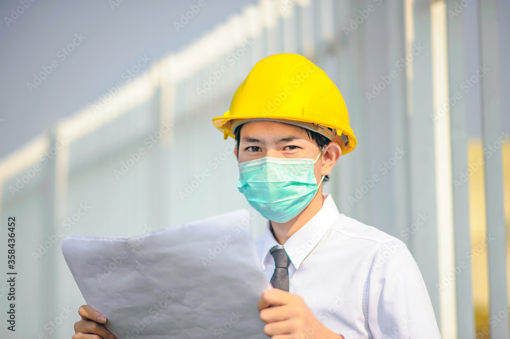 Businessman Manager use face mask Yellow hard hat holding blueprint work building construction Businessman Manager use face mask Yellow hard hat holding blueprint work building construction