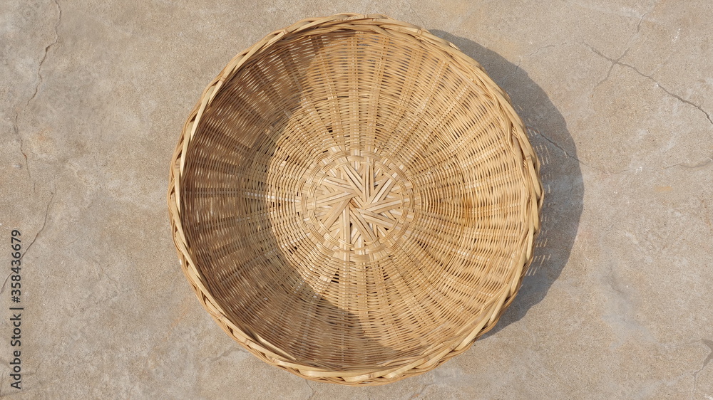 Empty round bamboo basket on the ground, top view, traditional handicraft