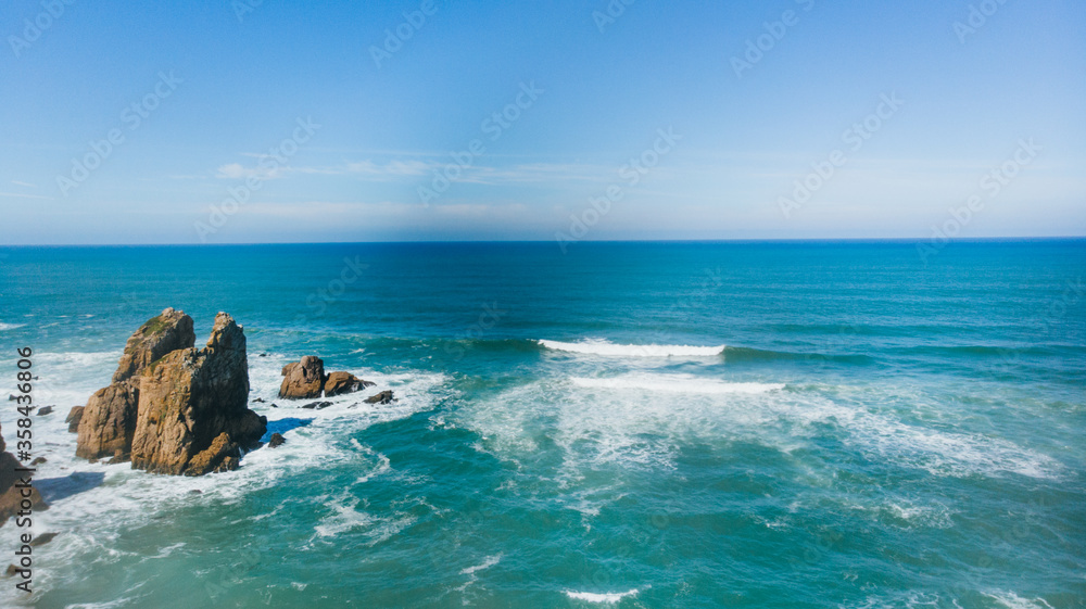 Portugal Ursa Beach at atlantic coast of Atlantic Ocean with rocks and sunset sun waves and foam at sand of coastline picturesque landscape panorama.