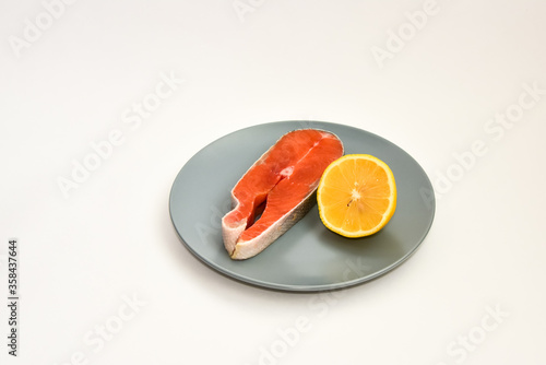 Fresh raw salmon steak with lemon slice isolated on white background