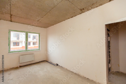 A small room that hasn t been finished yet. The non-renovated rooms. New building. The walls are plastered  the floors are concreted. There is a posting