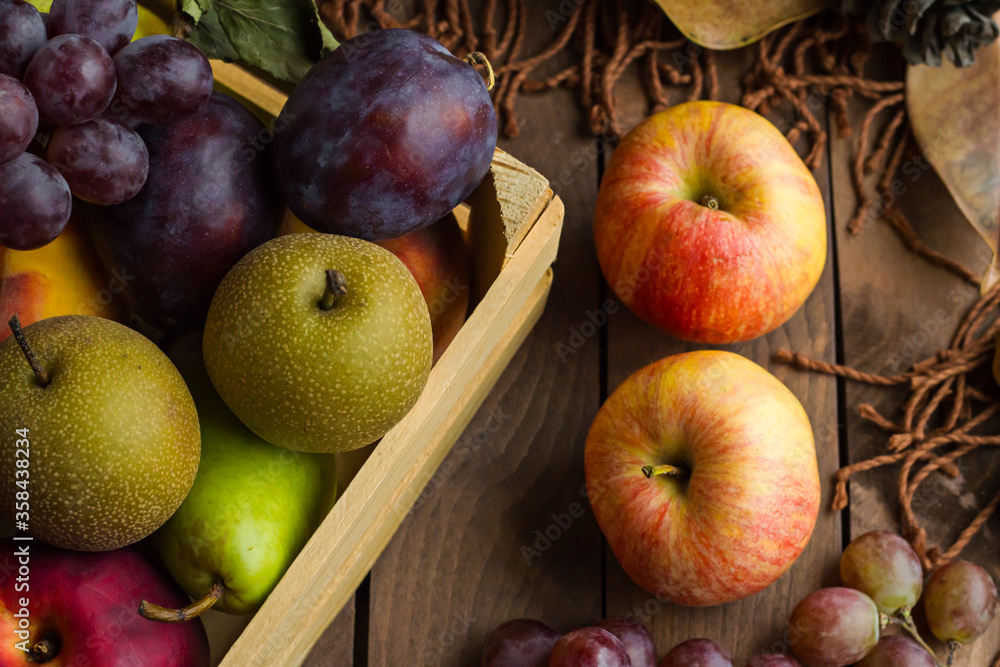 Fresh,ripe apples on wooden table in front of fruits in mini wooden box with scarf.