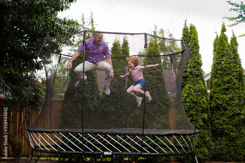 Father and daughter jumping on a trampoline