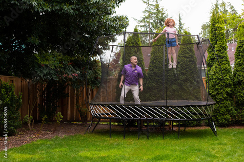 Father and daughter jumping on trampoline