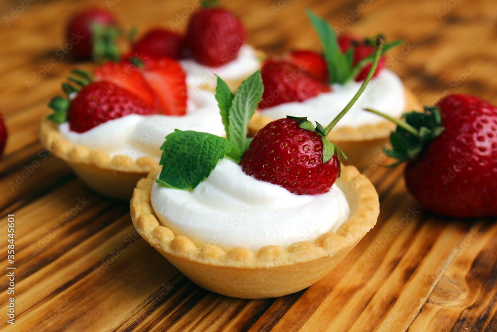 Tartlets with cream and strawberries on a wooden table Tartlets with cream and strawberries on a wooden table