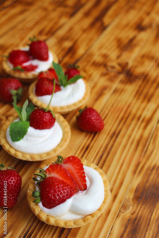 Tartlets with cream and strawberries on a wooden table Tartlets with cream and strawberries on a wooden table