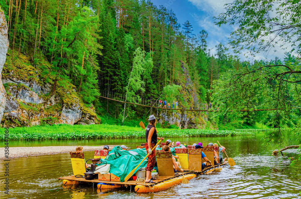 Fototapeta premium People are floating on an inflatable raft on the river among the mountains.