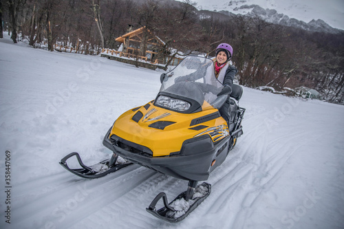 Blond young woman driving snowmobile