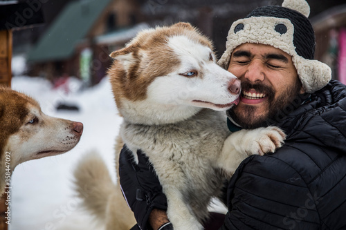 Man playing outside with husky in winter