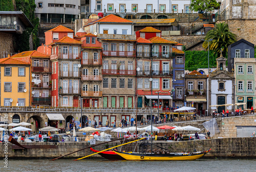 Traditional Portuguese houses with Azulejo tile in the Ribeira and tourist rabelo boat docked on Douro in Porto Portugal