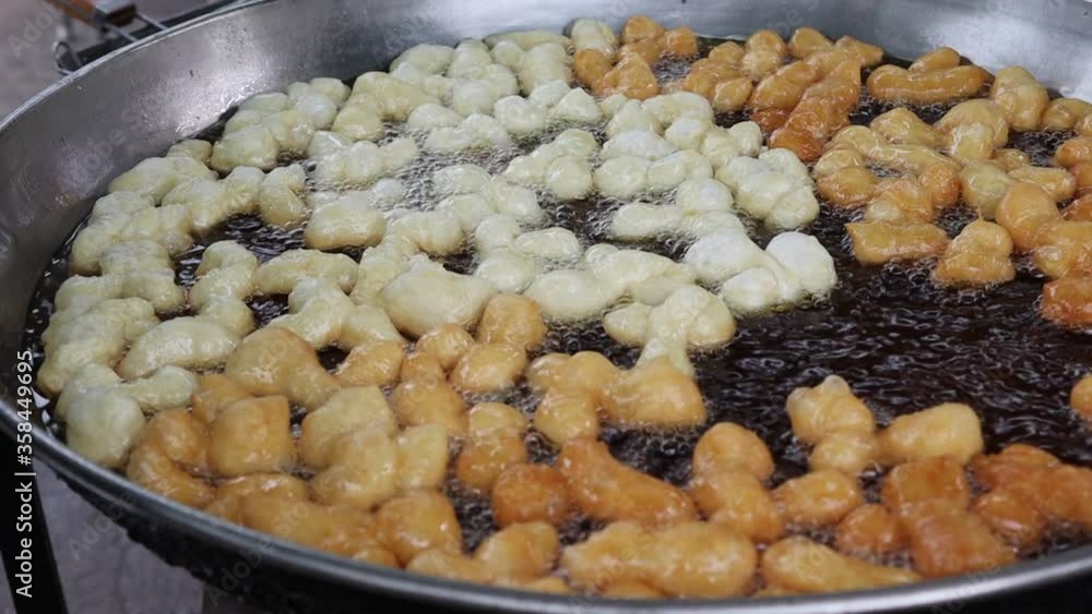 Making deep fried dough stick in metal pan and hot oil closeup. Is a morning snack for Thai people to eat with coffee or milk. Making deep fried dough stick in metal pan and hot oil closeup. Is a morning snack for Thai people to eat with coffee or milk.