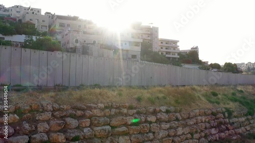 Palestine Refugges Camp Behind Concrete wall with sun flares-aerial
Dolly shot,Anata,Jerusalem,June,2020
 photo