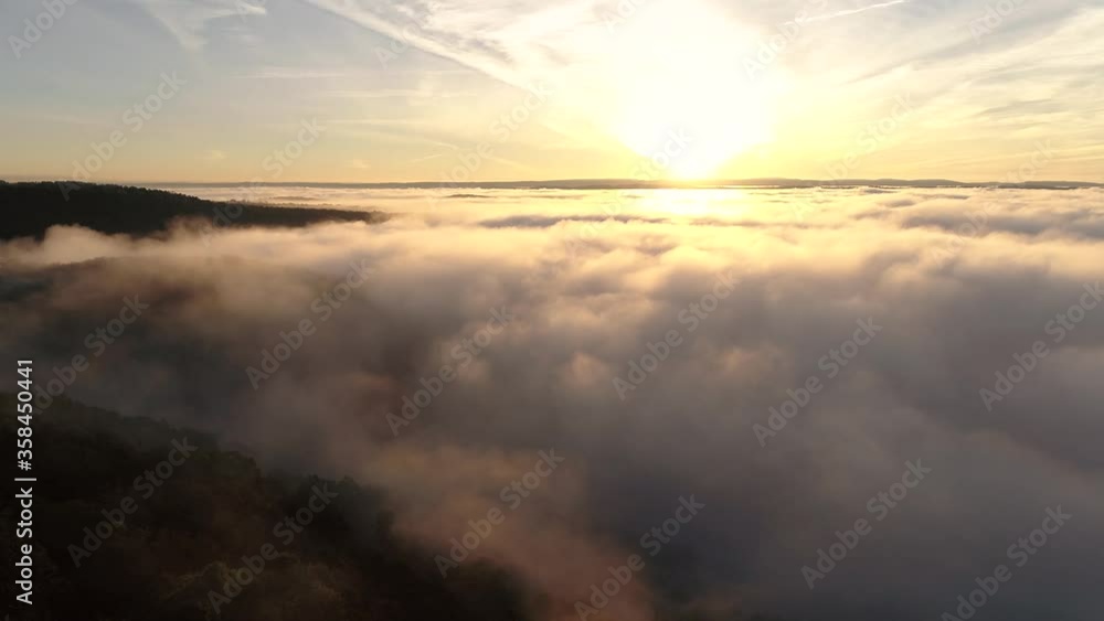 Aerial tilt reveal shot of clouds back lit by golden sunset in the horizon Aerial tilt reveal shot of clouds back lit by golden sunset in the horizon