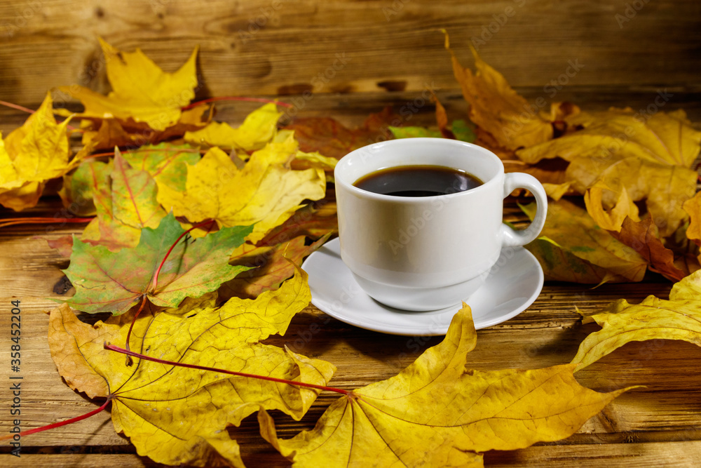 Cup of coffee and autumn maple leaves on wooden table. Autumn concept Cup of coffee and autumn maple leaves on wooden table. Autumn concept