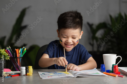 Happy little kid at the table draw with water color Learning and education of kid. photo