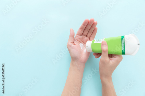 Woman hand holding cream tube and applying moisturizer cream on her beautiful hands. top view