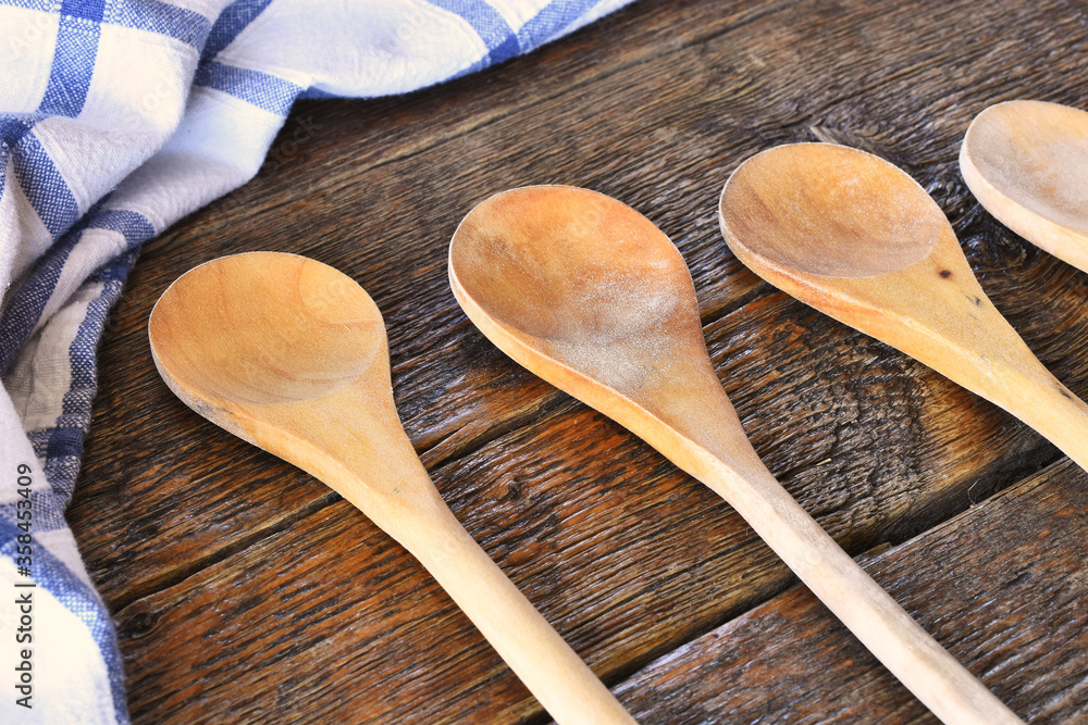 A close up image of several wooden mixing spoons and a blue and white dish towel. A close up image of several wooden mixing spoons and a blue and white dish towel.